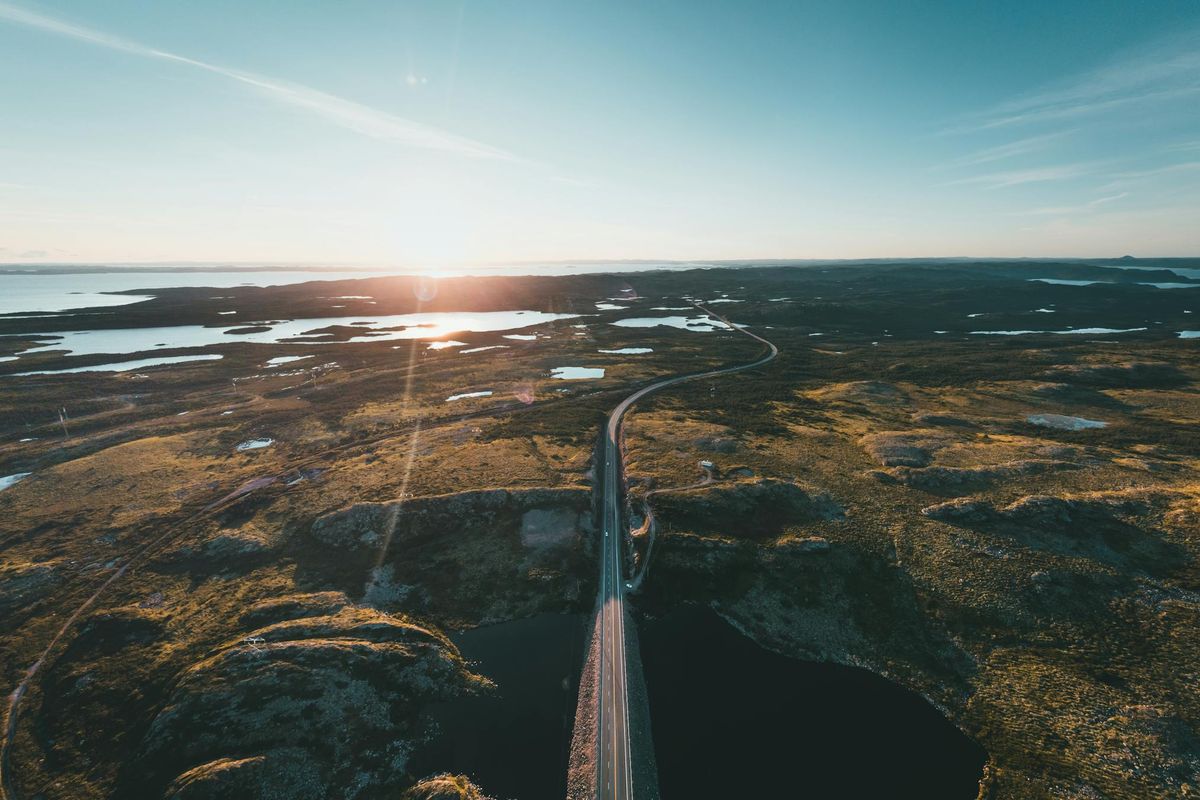 Road leading toward a sunrise horizon representing forward momentum and long-range growth