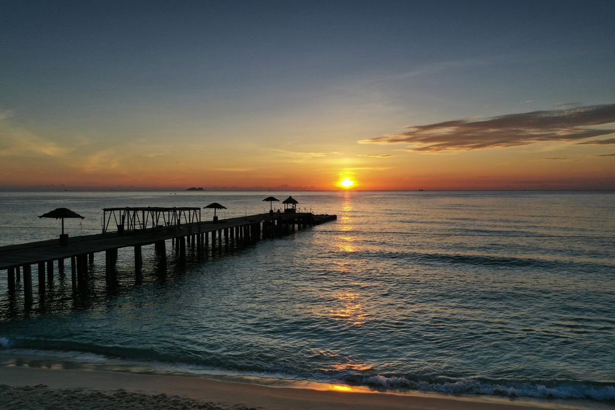 Pier extending toward a sunrise horizon over calm water to represent a clear path to next-stage growth
