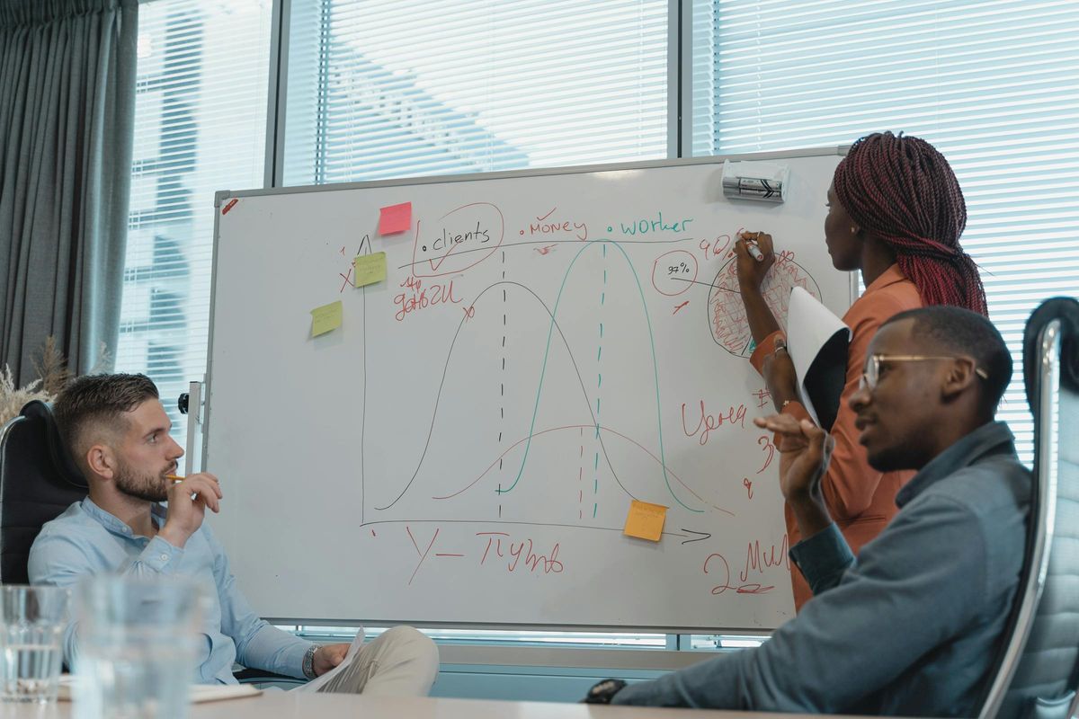 Leadership team working through operating model decisions at a whiteboard with system flow diagrams
