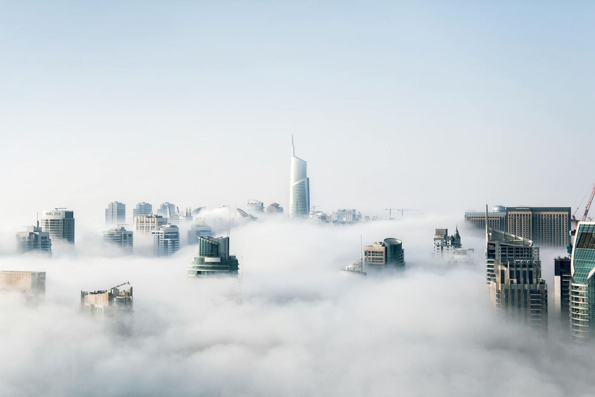 City towers rising through low cloud cover representing coordinated teams operating at different layers
